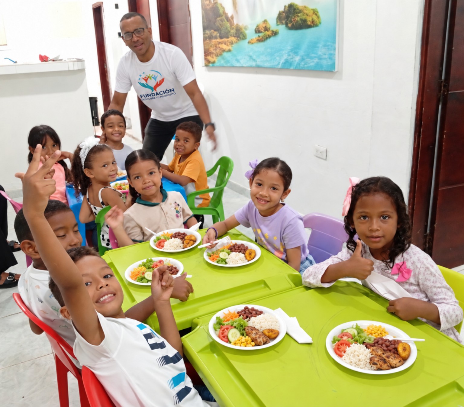 Niños de la Fundación compartiendo alimentos acompañados por un adulto de la Fundación